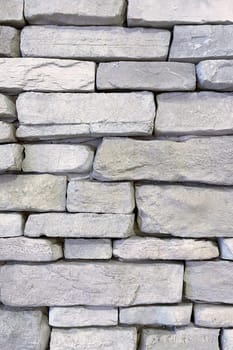 Textured Stone Wall Background.A close-up view of a textured stone wall. The wall is constructed from irregularly shaped, light-colored stones that are stacked in a horizontal pattern.