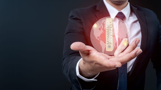 The business hand shows a virtual earth and thermometer with a high or heat temperature indicator. Concepts of environmental protection, climate change, or global warming