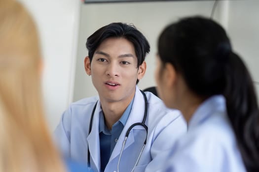 A doctor is engaged in a collaborative discussion with colleagues during a healthcare planning meeting, focusing on patient care and strategies in a clinical environment.