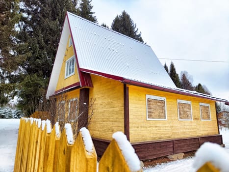 Snow and ice blanket the roof of a house, emphasizing the risks of falling snow, ice, and icicles during winter.