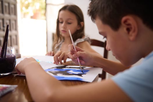 Children immersed in painting activities, cultivating creativity and artistic expression around a shared table.