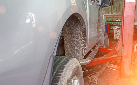 Side view of a car lifted off the ground by a large jack.