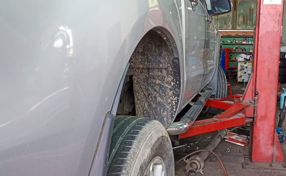 Side view of a car lifted off the ground by a large jack.