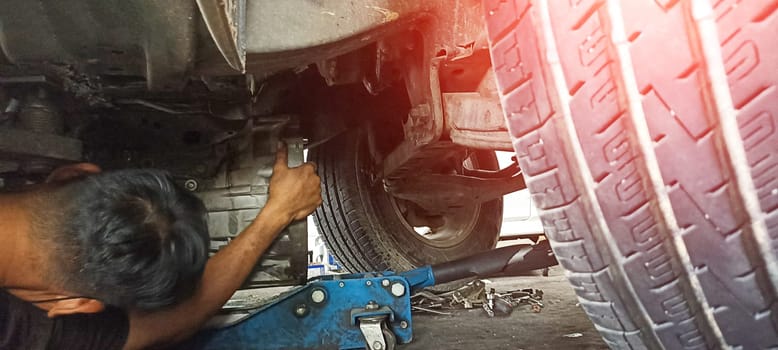 Car undercarriage and mechanic repairing undercarriage of the car