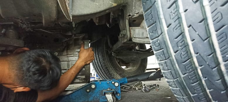Car undercarriage and mechanic repairing undercarriage of the car