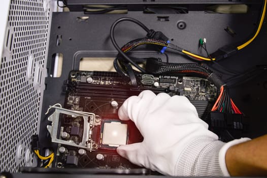 Image of a technician inserting a CPU chip onto a computer motherboard.