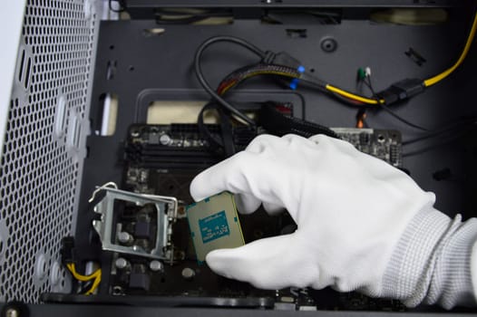 Image of a technician inserting a CPU chip onto a computer motherboard.