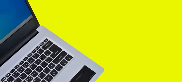 top right view of white laptop on yellow background