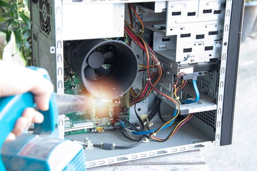 Cleaning a dusty computer with a blower.