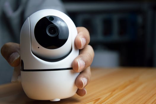 White ip camera lies on wooden floor, man using ip camera