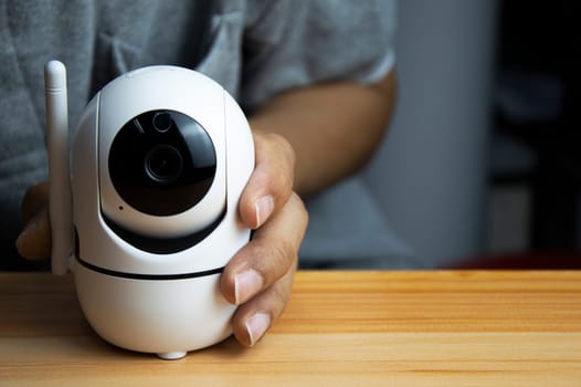 White ip camera lies on wooden floor, man using ip camera