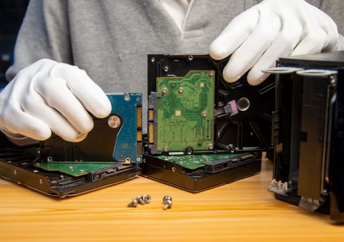 Rotating hard drives are still popular in use today, the technician is holding a hard drive in hand.