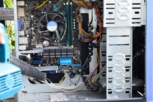 Photograph of a technician blowing dust from a computer