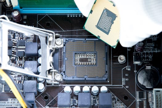 Top view of motherboard and technician about to insert CPU chip.
