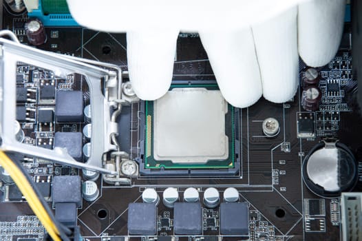 Top view of motherboard and technician about to insert CPU chip.