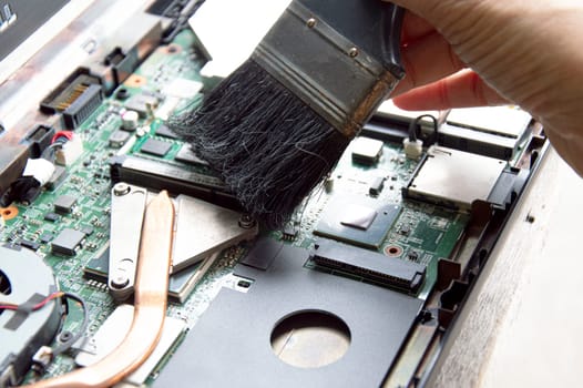 technician using brush Clean dusty notebooks.