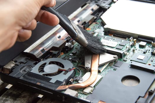 technician using brush Clean the dusty notebook.