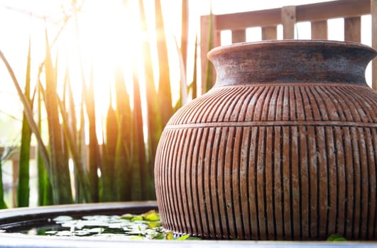 The evening sun shines on the water basin where the jar is placed inside.