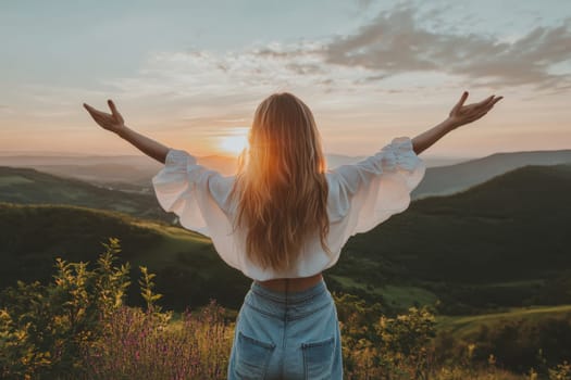 A woman is standing on a hillside, with her arms outstretched and the sun shining on her. Concept of freedom and joy, as the woman is embracing the beauty of nature and the warmth of the sun