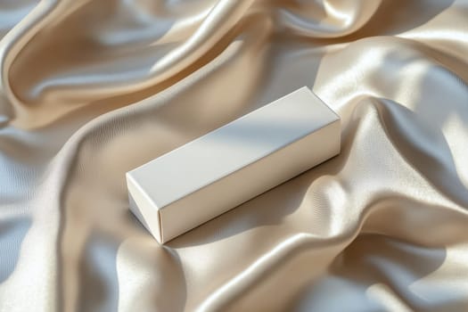 A white box is on a piece of silk fabric. The box is empty and the fabric is smooth and shiny