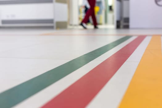 Colorful guide lines on the floor of the hospital corridor for navigation with a blurred hospital background.