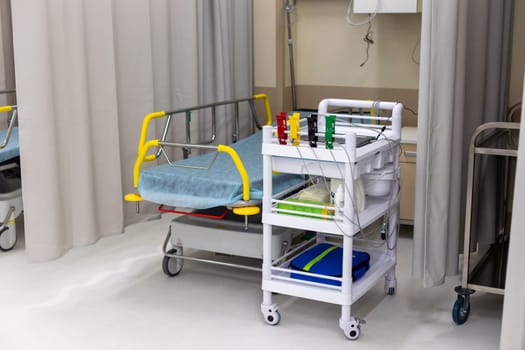 Modern hospital room, in the emergency department, equipped with a bed for the patient and a medical trolley with supplies
