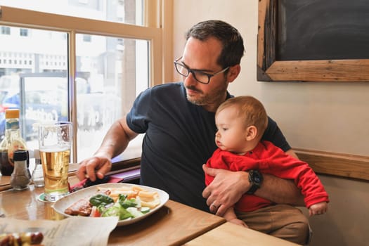 Father and his baby son eating in a restaurant