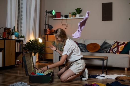 In a cluttered living room, a woman organizes her suitcase, excitedly preparing for her next adventure