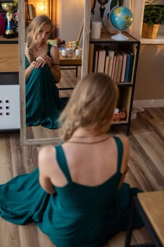 A woman in a beautiful green dress stands before a mirror, reflecting a serene and introspective moment
