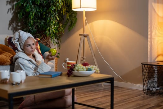 A woman is savoring a cozy, relaxing evening at home surrounded by fresh fruits and a tranquil ambiance