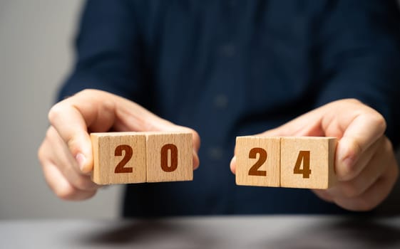 Businessman holding wooden blocks 2024. Business plan and strategy concept. Planning. Targets and goals. Financial plans, performance