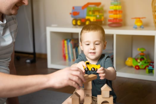 Little toddler boy 2.5 years playing wooden blocks and toy cars with dad. Spending time with children. Educational activities for kids. Children's room. Indoors