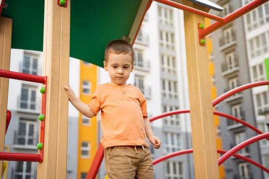 Cute toddler boy two or three years old is playing on the playground in a residential complex. Healthy summer activity for children. Children's games. Selective focus