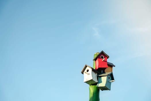 Wooden small bird houses and birdhouses against the blue sky. Real estate and affordable housing concept. Mortgage, loan, taxes. Buying, selling and renting apartments. Copy space