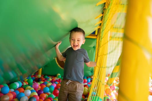 Happy smiling toddler boy playing in children's playroom. Active lifestyle, childhood. Selective focus