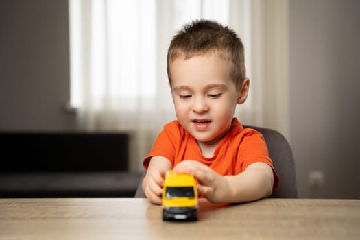 Cute toddler boy playing with a toy yellow car. Children's leisure and lifestyle. Childhood. Focus on the child.