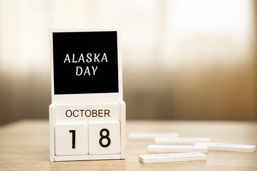 Calendar with words October 18 - Alaska Day in the U.S. state. Table and wooden blocks