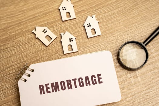 Remortgage concept. Process of paying off your mortgage with the proceeds from a new mortgage using the same property as security. wooden houses on the table and notes