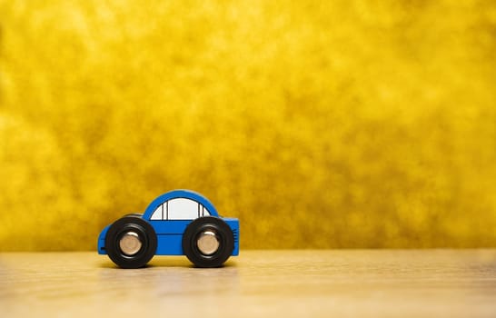 A small blue toy car on a yellow background. The concept of auto insurance, buying and selling cars. Repair and maintenance of vehicles. Copy space