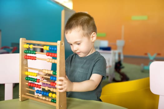 Cute toddler boy playing with colourful toy abacus in a children's entertainment center. Educational toys for children. children's pastime