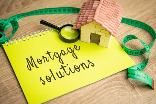 Mortgage Solutions concept. Assistance in purchasing a new home, refinancing existing mortgages and reduce their monthly payments. Real estate and loan rates. Notes and miniature house