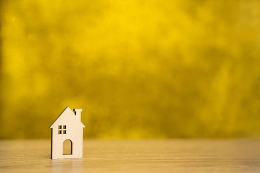 Miniature wooden house on a yellow background. Real estate and affordable housing concept. Mortgage, loan and insurance of apartments. Selling and buying home. Copy space