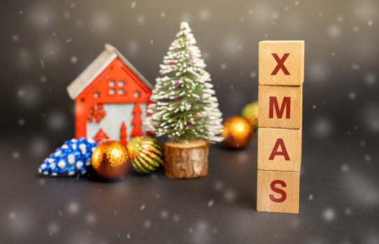 Wooden blocks with the word Xmas, miniature house and a Christmas tree. New Year or Xmas winter holiday. Decoration, celebration. The concept of the beginning of the new year. Snow, snowfall