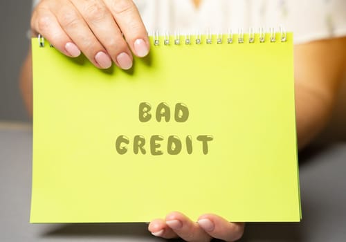 The inscription Bad credit in a notepad. Credit and loan concept. Business and finance. Woman's hand holding a notepad