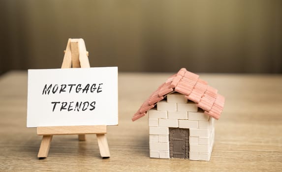 Easel with Mortgage trends concept and a miniature house. Mortgage rates and the latest news about their changes. Housing loan and real estate. Business and finance