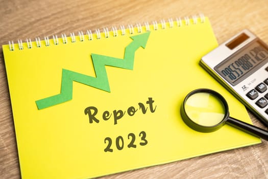 Report 2023 and up arrow. Successful financial reporting of the company. Profit and revenue growth. Business and finance concept. Calculator, notepad and magnifying glass