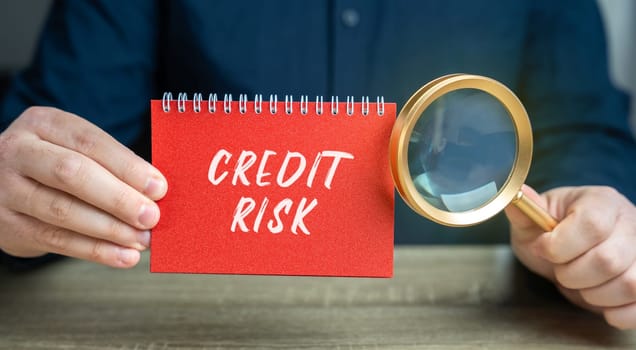 Credit risk concept. Financial loss resulting from a borrower's failure to repay a loan. Business and finance. Notepad and magnifying glass in the hands of a businessman