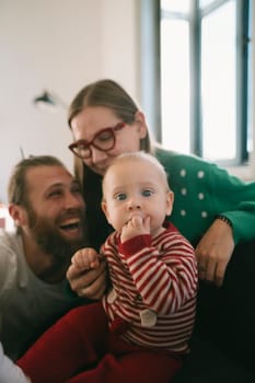 Capturing a joyful family moment featuring loving parents and their playful baby in a warm, cozy setting