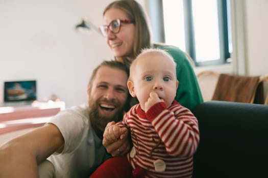 A joyful family is happily bonding with their adorable baby, showcasing deep love and warmth in a cozy atmosphere