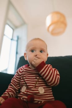 An adorable baby wearing a colorful striped holiday outfit, captured in a warm and cozy indoor setting